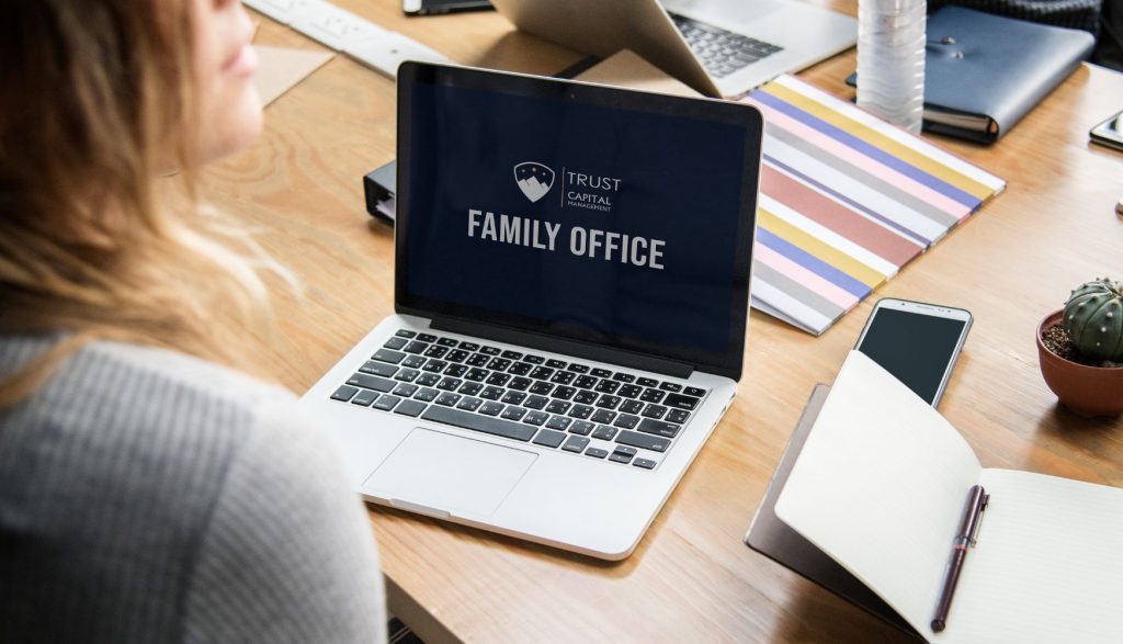אישה מסתכלת על מחשב שכתוב familt office טראסט קפיטל